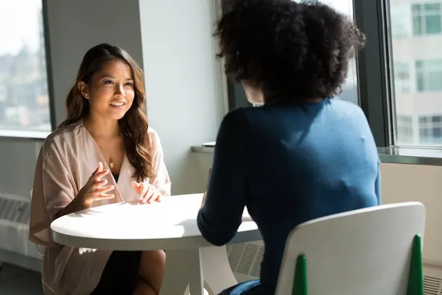 Zwei Frauen im Gespräch an einem Tisch